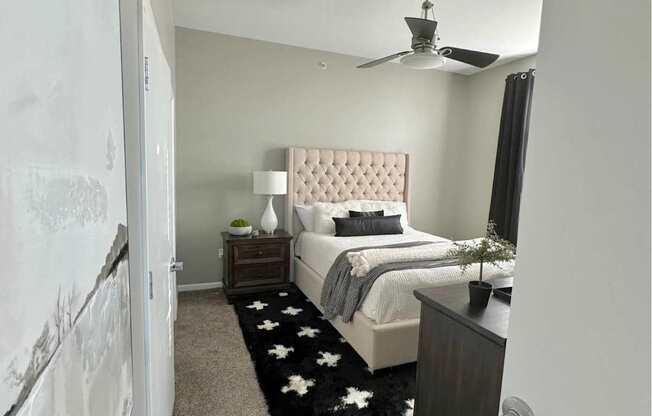 A bedroom with a bed, nightstand, and a rug with white stars.