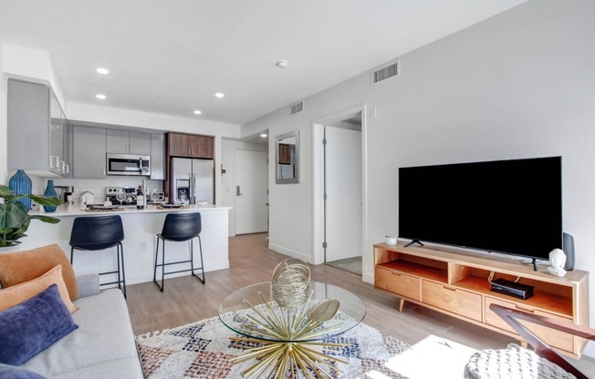 a living room with a tv and a kitchen in the background