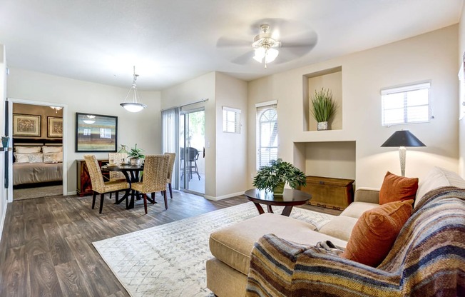 A living room with a couch, a dining table, and a ceiling fan.