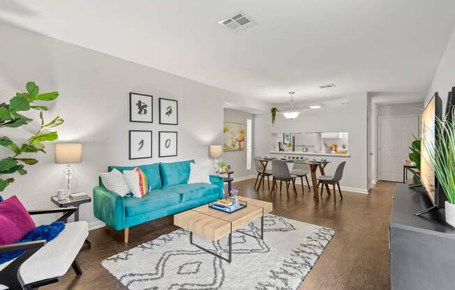 A living room with a blue couch and a rug.
