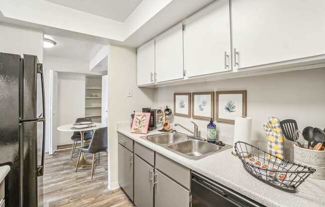 A kitchen with a black refrigerator and white cabinets.