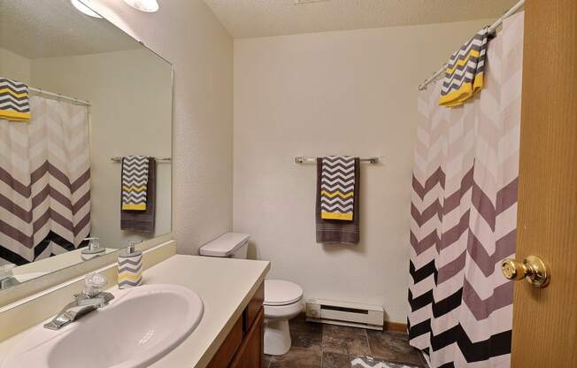 a bathroom with a sink and a shower and a toilet. Fargo, ND Kennedy Apartments