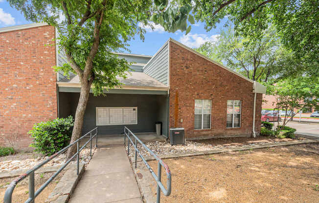 A brick building with a metal roof and a tree in front.