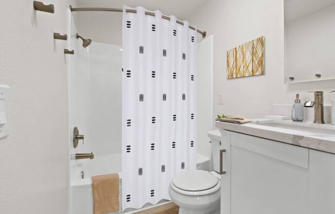 a bathroom with a white sink and toilet and a shower with a shower curtain