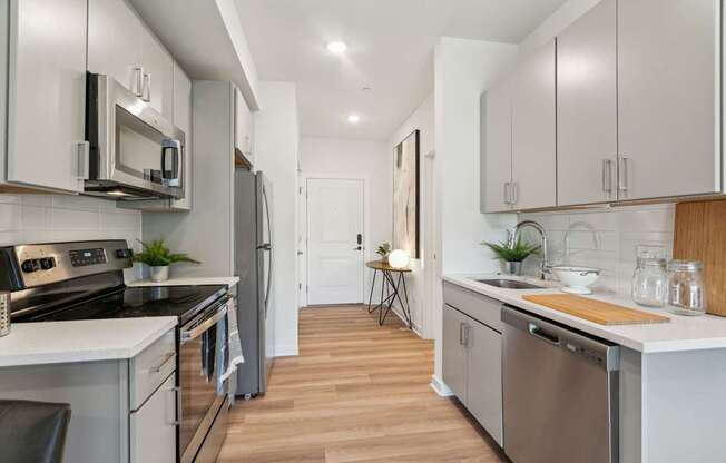 A modern kitchen with stainless steel appliances and wooden floors.