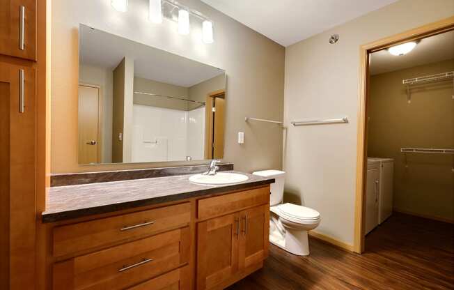 a bathroom with a toilet and a sink and a mirror. Fargo, ND Urban Plains Apartments