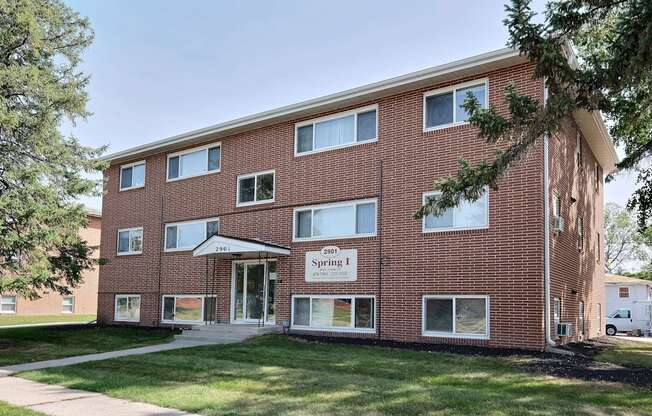 a brick building with a sidewalk in front of it. Fargo, ND Spring Apartments