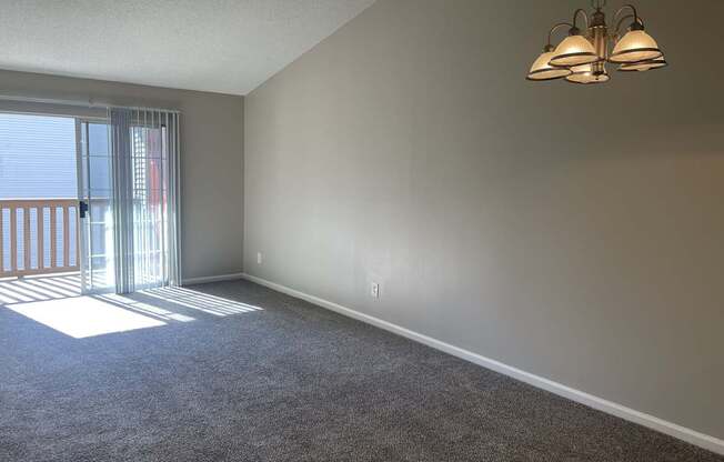 A room with a carpet floor and a window with blinds.