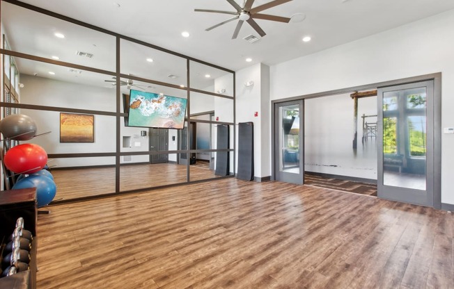 a workout room with a ceiling fan and sliding glass doors