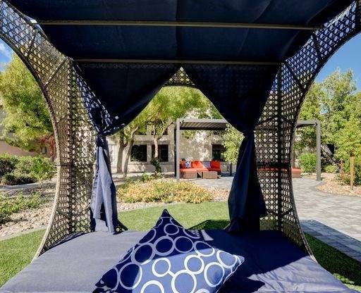 A canopy bed with a blue pillow and a canopy with a pattern on it.