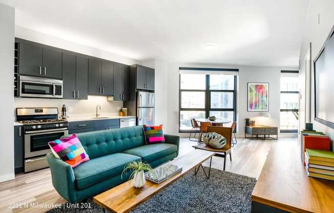 a living room with a blue couch and a kitchen with black cabinets