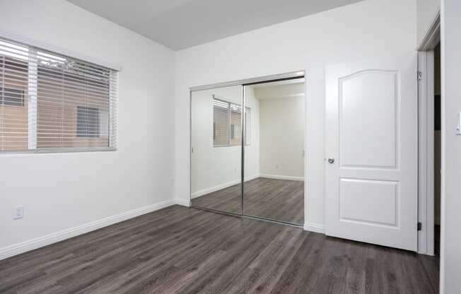 a bedroom with hardwood floors and white walls