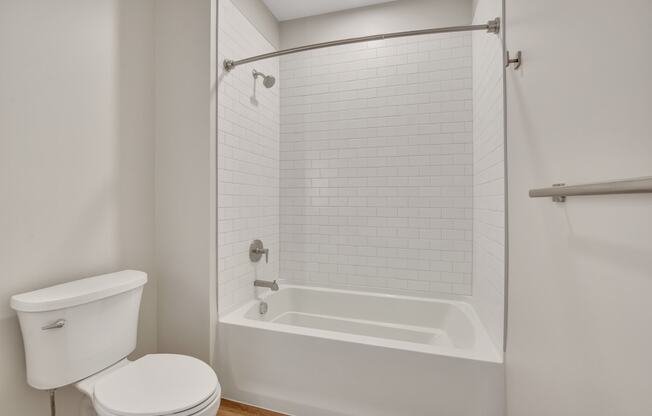a bathroom with a white toilet and a white tub with a shower curtain