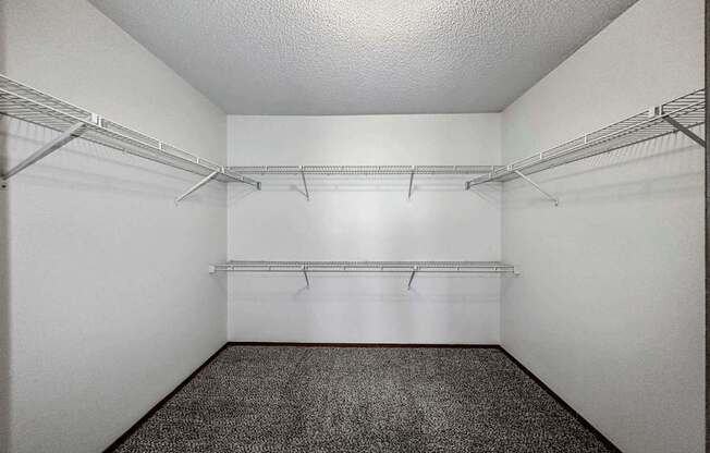 the walk in closet of an empty room with shelves