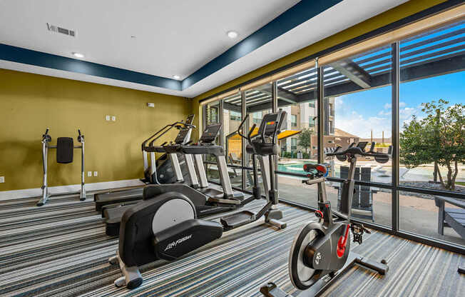A gym with a yellow wall and a row of treadmills.
