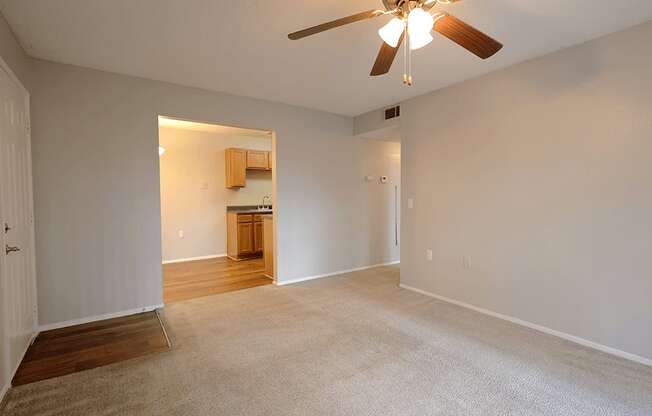 an empty living room with a ceiling fan