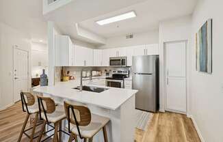 A modern kitchen with a white island and wooden chairs.
