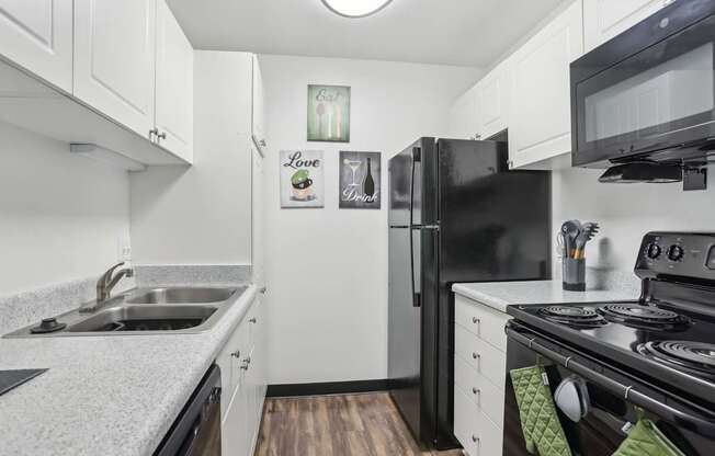 A black refrigerator sits in a kitchen with white cabinets.