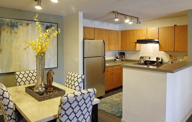 Ardenne Apartments kitchen and dining room with blue and white chairs, yellow flowers and stainless steel appliances