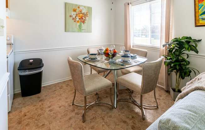 a dining area with a glass table and chairs and a window