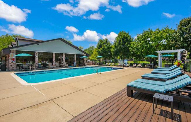 A pool with sun loungers and a building in the background.