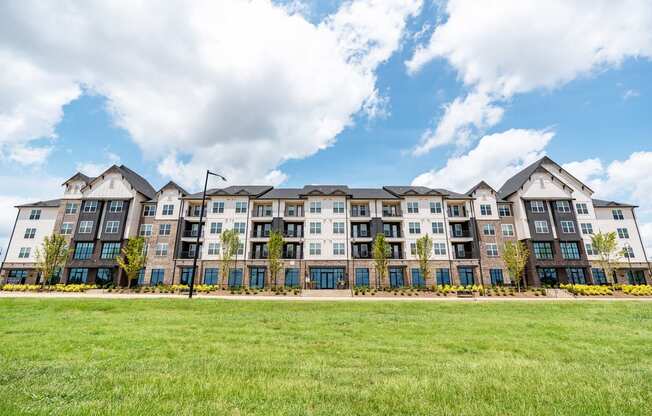 a large apartment building with a green lawn in front of it