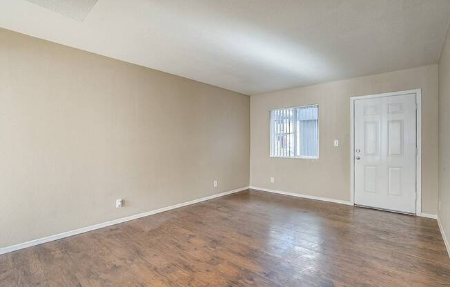 Empty room with wooden flooring and white door.