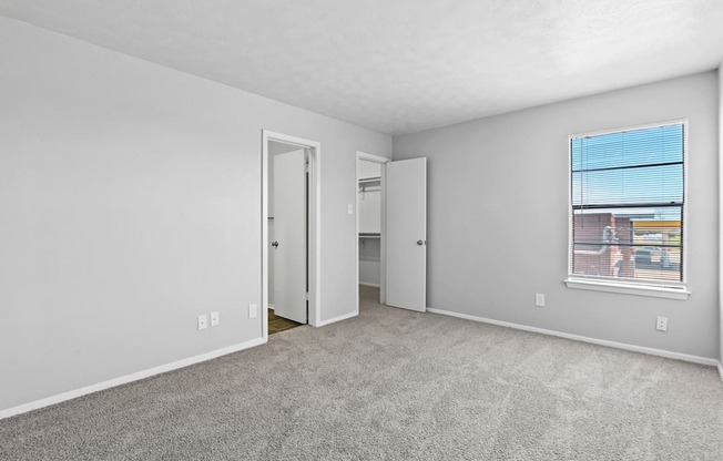 a bedroom with a large window and carpeted flooring