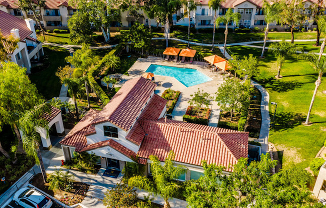 A house with a red tiled roof and a pool in the backyard.