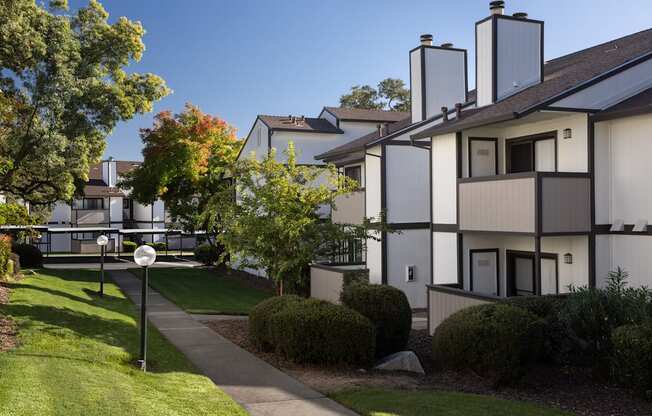 A white building with a black roof and a sign on the lawn.