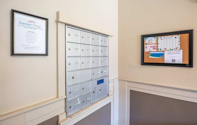 a wall of mailboxes and a bulletin board on the wall of a hallway