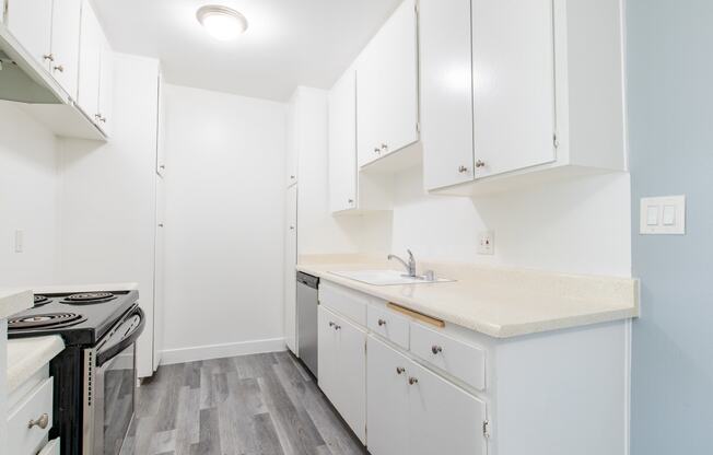 a white kitchen with white cabinets and a stove and sink