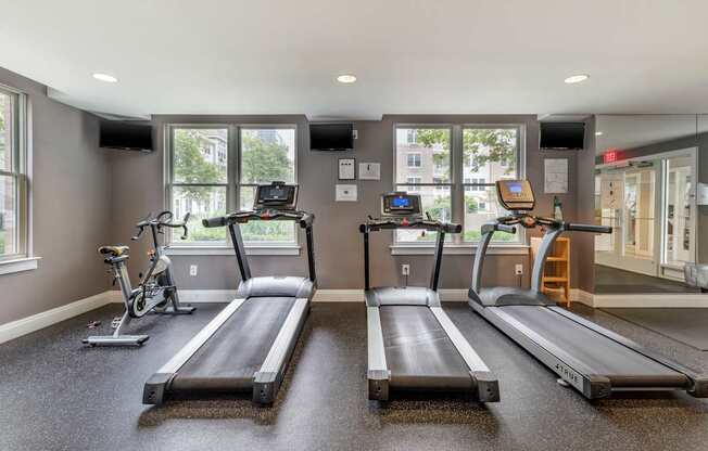 two treadmills and two bikes in a gym with windows at Pier Village Apartments, New Jersey, 07740