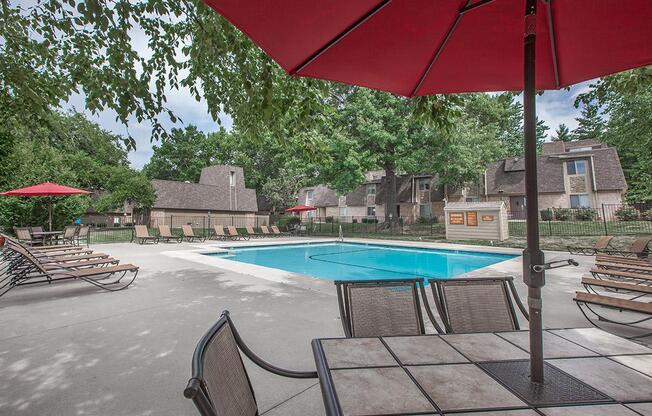 An outdoor dining area with umbrella shade by the outdoor pool at Preston Court.