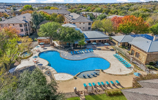 A large swimming pool surrounded by a grassy area and trees.