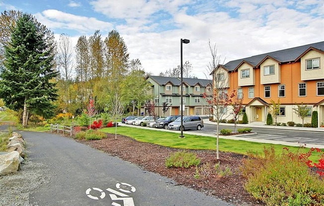 Kenmore, WA, Apartments for Rent - Northshore Townhomes - Bike Path and Building Exterior with View of Parking Lot and Surrounded by Beautiful Landscaping and Trees.