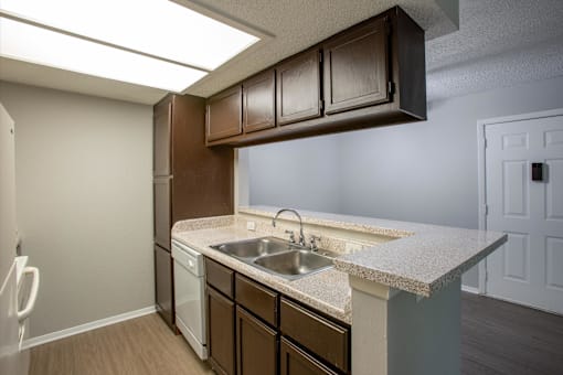A kitchen with brown cabinets and a white sink.