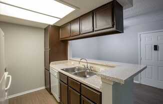 A kitchen with brown cabinets and a white sink.
