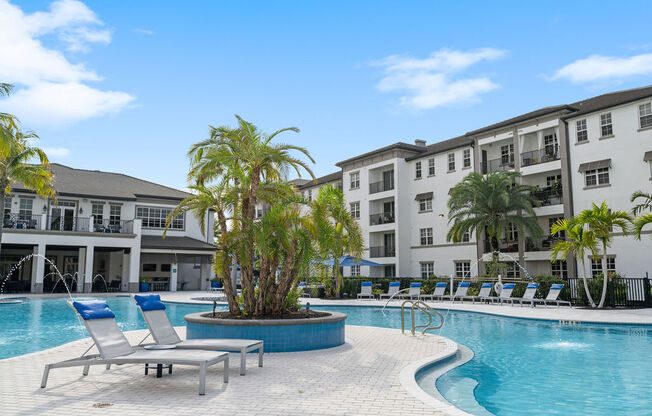 The pool with many lounge chairs and islands with palm trees