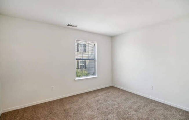 A room with a window and carpeted floor.