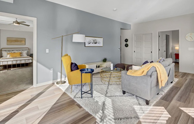 a living room with a gray couch and yellow chairs