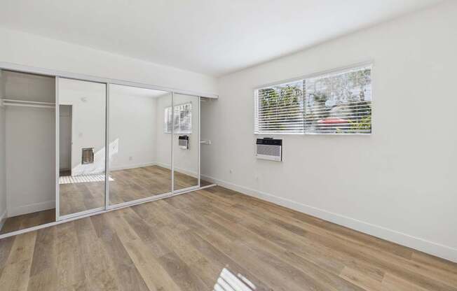 A room with a sliding glass door and wooden flooring.