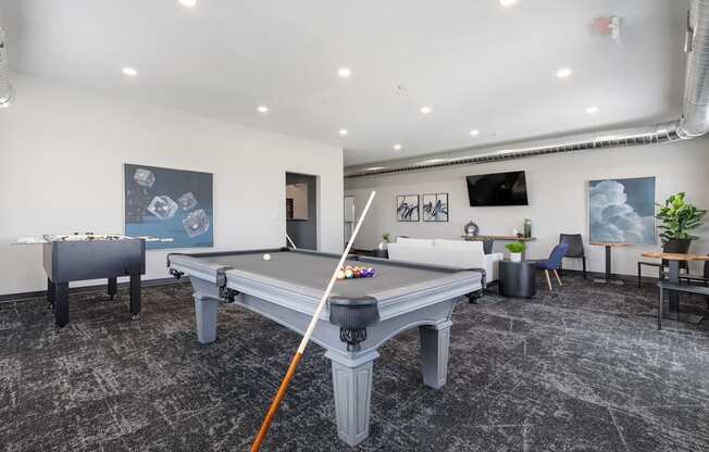 A pool table in a room with a chair and a plant.