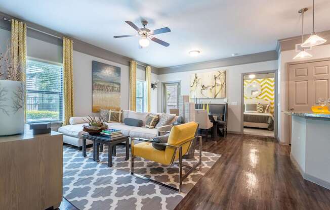 A living room with a yellow chair and a grey and white patterned rug.