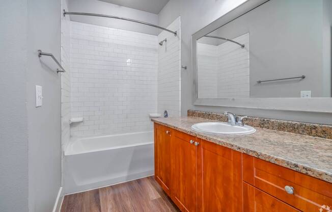 A bathroom with a white tiled shower and a wooden vanity.