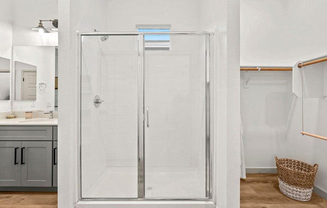 A white bathroom with a walk-in shower and a white sink.