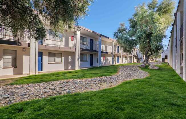 A row of apartment buildings with a grassy area in front.