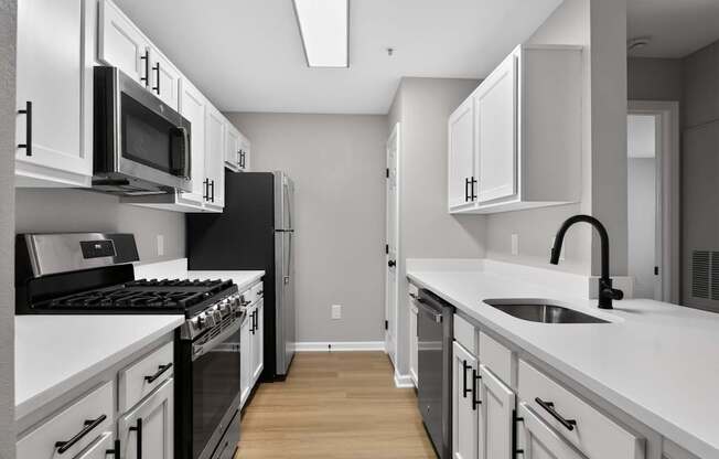 A modern kitchen with white cabinets and black appliances.