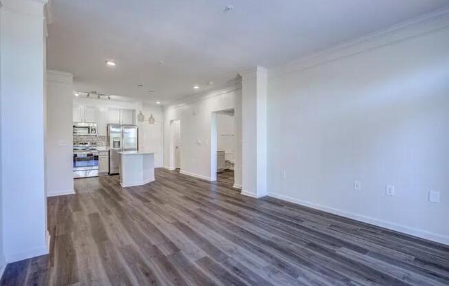 A spacious room with wood flooring and white walls.