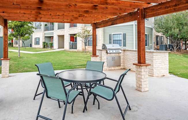A patio with a table and chairs under a wooden pergola.
